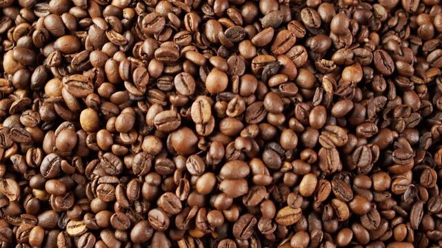Freshly roasted coffee beans falling from above onto large pile creating dynamic movement for organic food background caffeine energy advertising ingredient and industrial production process