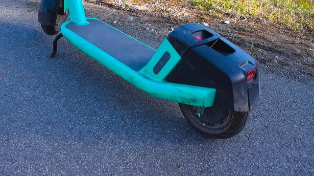 Modern electric rental scooter parked on an asphalt road in a city, providing an eco friendly and convenient urban mobility sharing service for short distance transportation on a sunny day
