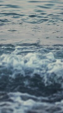 Closeup shot of ocean waves with varying intensity, showcasing dynamic motion of water. Frames capture breaking wave with white foam and splashes. Other frames depict gentle ripples on water surface c