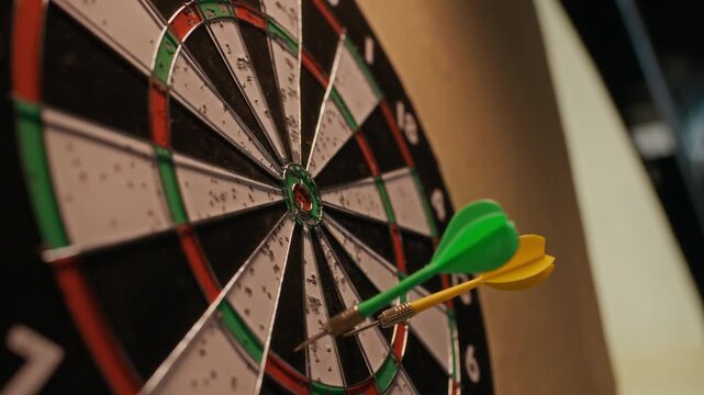 Extreme close up of colorful darts hitting dartboard then unrecognizable Black man taking them back during casual game at bar