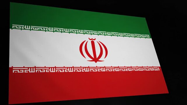 Close up view of the national flag of the Islamic Republic of Iran featuring the red emblem and Kufic script.