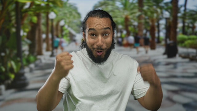 Man pointing finger at camera on street with pointing hand and open mouth expression; joy victory celebration.