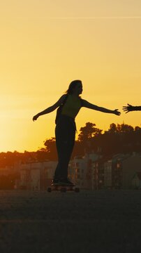 Silhouette of women roller skating and longboarding during sunset