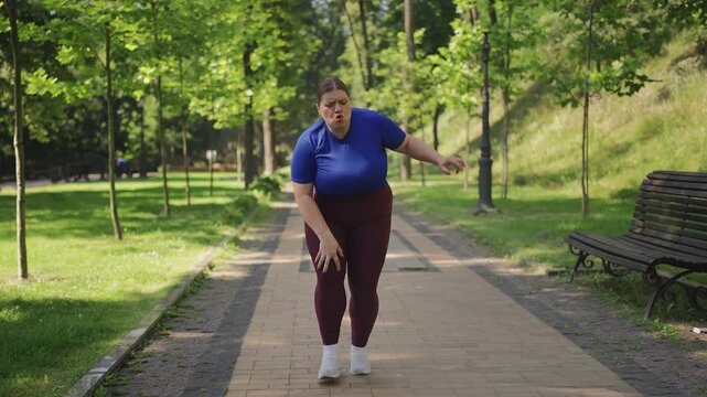 Young large-bodied woman feeling knee pain while jogging in park, tendonitis