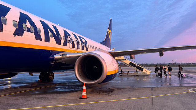 Ryanair jet on wet apron at BER airport at dawn with passengers boarding