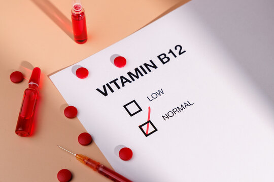 Vitamin B12 vials with red tablets and medical form on cream gradient for metabolic health, energy recovery and professional wellness.