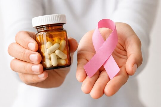 Hands holding a bottle of capsules and a pink ribbon, symbolizing breast cancer awareness and medical treatment.