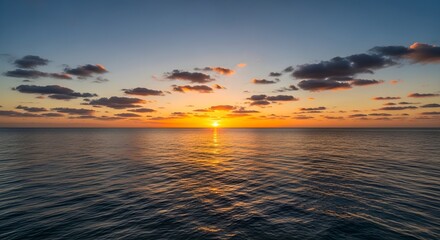 Obraz premium Serene sunset over the ocean with scattered clouds reflecting golden light on the rippling water surface