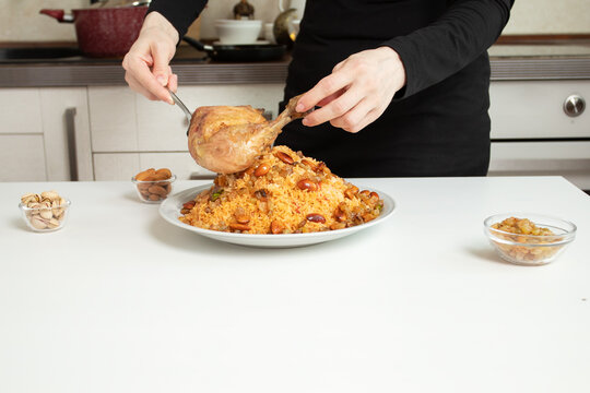 Roasted chicken leg being placed on spiced rice with nuts and raisins