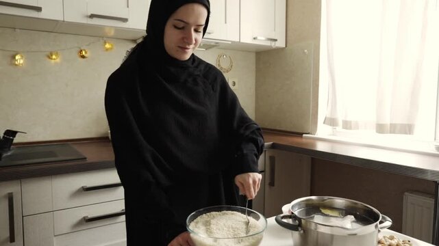 smiling muslim woman in black hijab stirring rice in a large bowl beside metal pot during home cooking and iftar preparation in bright kitchen