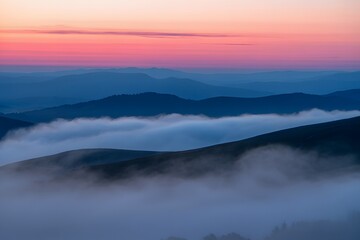 Fototapeta premium Sunset over mountains covered in misty clouds