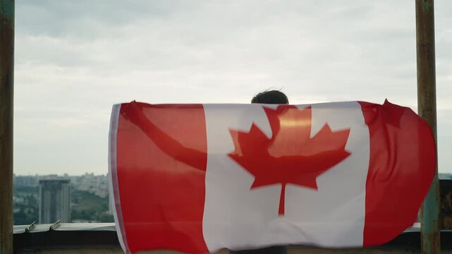 Young Black woman waving Canadian flag on rooftop, patriotic feelings