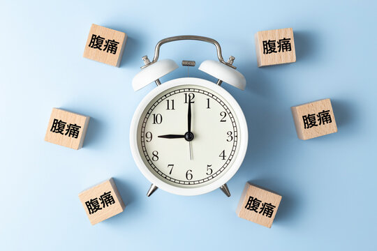 「腹痛」と書かれたのブロックと目覚まし時計