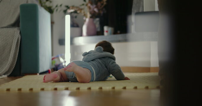 Baby lying on mat reaching forward with arm extended, exploring surroundings in cozy living room, concept of movement, curiosity, and early physical development