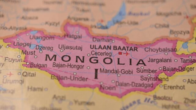 Man Marking Mongolia Location with Green Pin on Paper World Map in 4K 60fps Close-Up