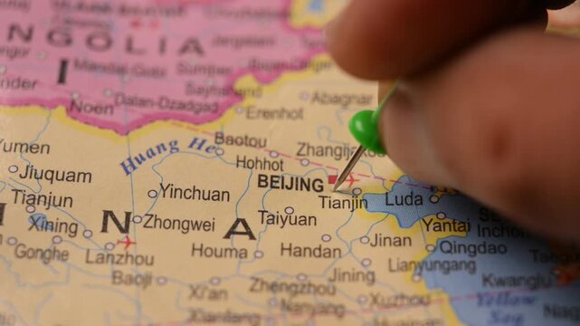 Man Marking Beijing Location with Green Pin on Paper World Map in 4K 60fps Close-Up