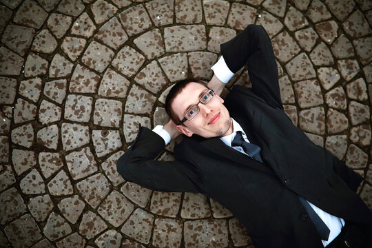 A man in a suit lies on a brick floor