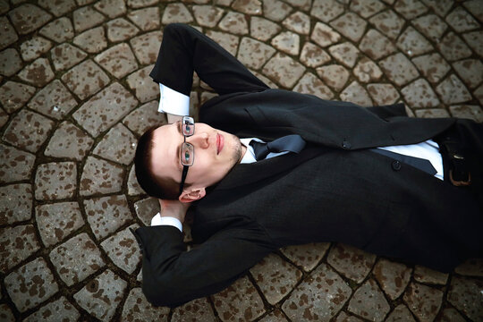 A man in a suit lies on a brick floor