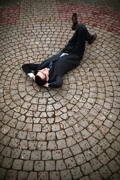 A man in a suit lies on a brick floor