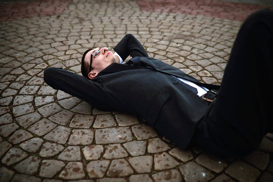 A man in a suit lies on a brick floor