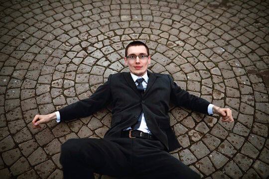 A man in a suit lies on a brick floor