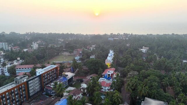 Wide cinematic aerial of a sunset scene blending ocean, sky, and lush greenery, as warm tones fade across the horizon and coastal settlements rest in soft evening light.