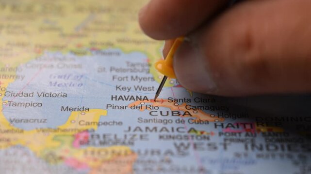 Man Marking Havana Location with Yellow Pin on Paper World Map in 4K 60fps Close-Up