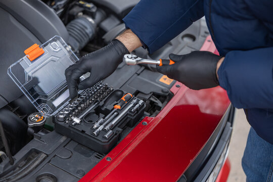 Using socket wrench and tool kit for car repair and maintenance under open hood
