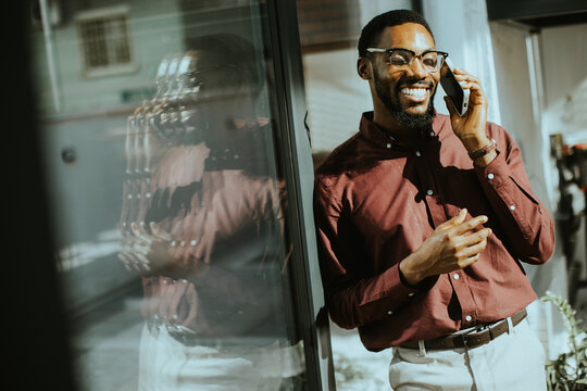Man talking on phone near window during daytime in urban setting