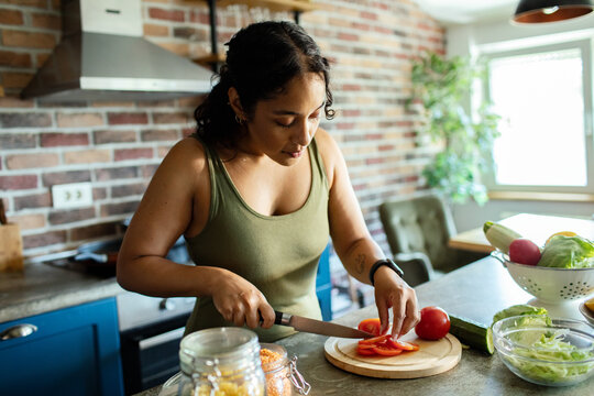 Woman slicing tomatoes in home kitchen