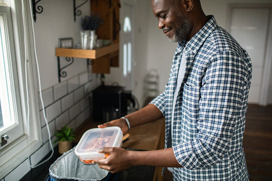 Man packing meal prep container in home kitchen