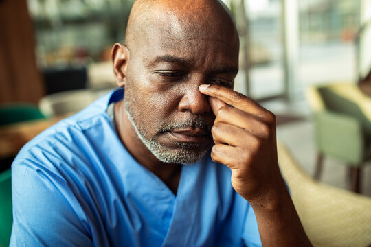 Tired healthcare worker pinching nose in hospital break room