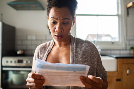 Concerned woman reading utility bill in home kitchen