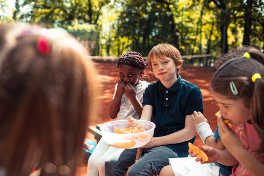 Children sharing orange slices at outdoor park snack