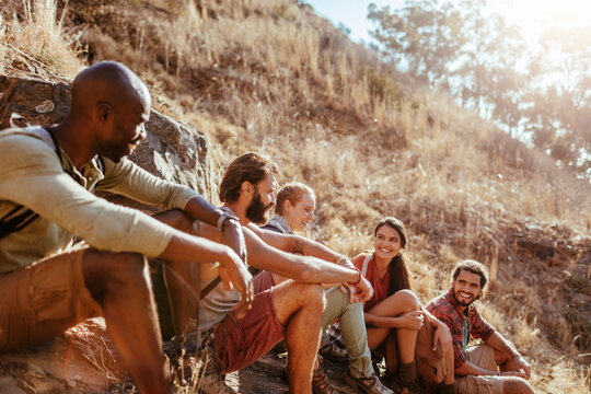 Group of friends resting during hike on sunny hillside