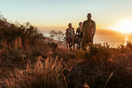 Group of friends hiking coastal trail at sunset