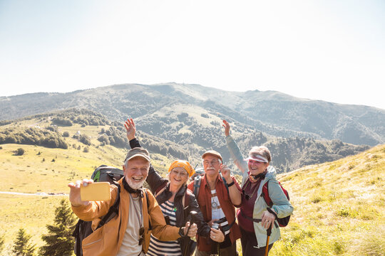 Happy senior friends hiking in sunny mountain landscape