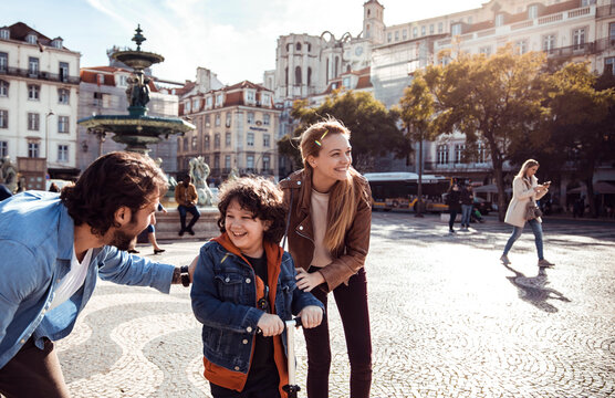 Happy family with scooter at sunny european city square
