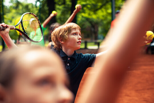 Focused boy practicing tennis on outdoor clay court