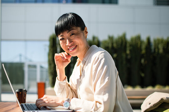 Smiling businesswoman working on laptop outdoors