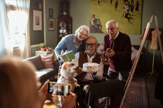 Senior friends celebrate birthday with dog at home