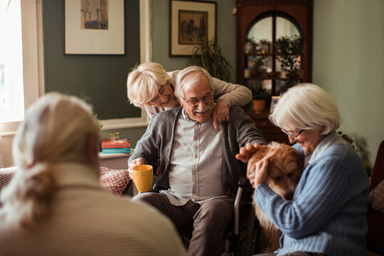 Senior friends socializing with dog in cozy living room