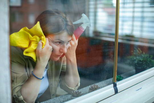 Woman cleaning apartment window with spray bottle
