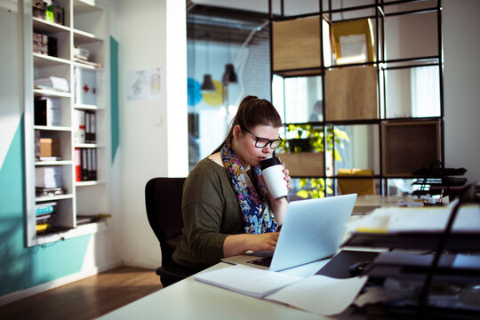 Young woman working on laptop in modern office