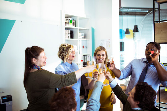 Coworkers toasting with champagne in modern office