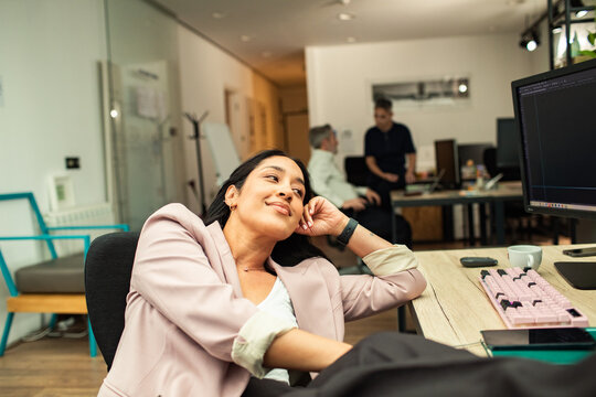 Smiling businesswoman taking a break at computer in open office