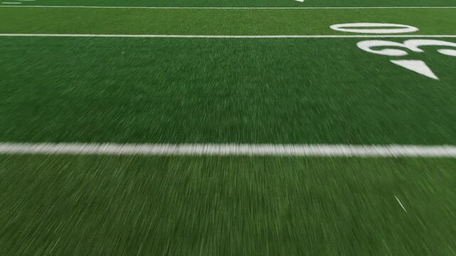 American football field low POV flyover showing yard lines and hash marks