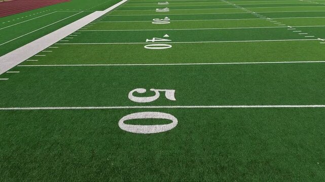 American football field low POV flyover showing yard lines and hash marks