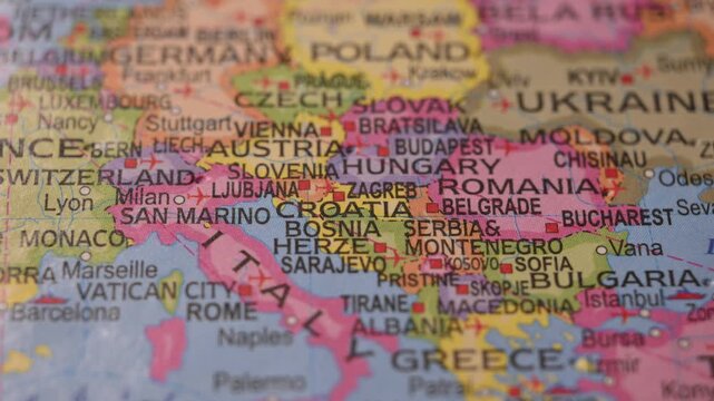 Hand Placing Green Pin on Croatia Location in Paper World Map Travel Concept