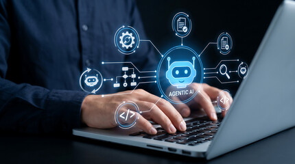Fototapeta premium Software developer using laptop with glowing agentic artificial intelligence interface showing autonomous task flow and code generation symbols in dark professional office environment